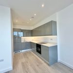 Modern kitchen with grey cabinets and wooden flooring.