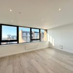 Empty bright room with large windows and wooden floor.