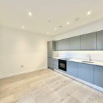 Modern kitchen with grey cabinets and wooden floor.