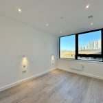 Bright empty room with wooden floor, city view.