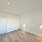 Empty room with wooden floor and wall lights.