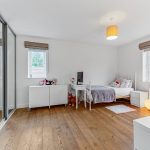 Bright, spacious modern bedroom with wooden flooring.