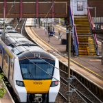 Modern train arriving at station with empty platforms.