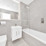Modern grey tiled bathroom with white fixtures.