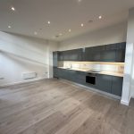 Modern kitchen with grey cabinets and wooden floor.