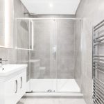 Modern grey tiled bathroom with shower and basin.