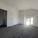Empty room with grey carpet and white walls.