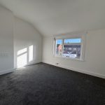 Empty room with grey carpet and large window.