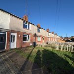 Row of terraced houses with gardens and path.