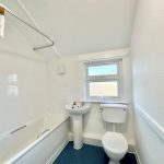 White bathroom with bath, sink, and toilet.
