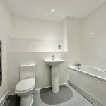 Modern white bathroom with tub and towel rail.