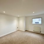 Empty carpeted room with window and white walls.