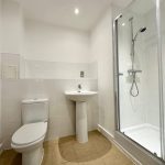 Modern bathroom with shower, toilet, and sink.