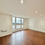 Spacious empty room with wooden flooring.
