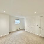 Spacious empty room with white doors and window.