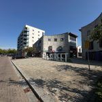 Modern city street with buildings and parked cars.