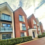 Modern residential building with balconies and blue sky.