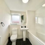 Modern bathroom with white fixtures and black tile floor.