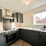 Modern kitchen with dark cabinets and large window.