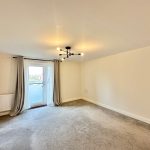 Spacious empty room with carpet and chandelier.
