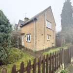 Stone cottage with garden and wooden fence.