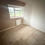 Empty room with wooden floorboards and window.