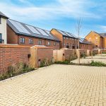 Modern houses with solar panels and paved driveway.