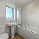 Modern bathroom with bathtub, sink, and window.