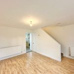 Spacious room with wooden floor and staircase.
