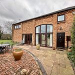 Brick house with patio and garden furniture.