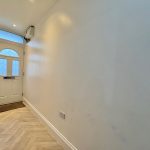 Bright narrow hallway with white walls and door.