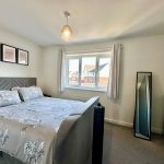 Modern bedroom with double bed and mirror.