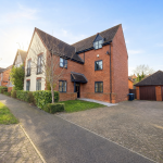 Modern red-brick house with driveway in suburban setting.