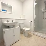 Modern bathroom with shower and white fixtures.