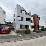 Modern townhouses with parked cars on cloudy day.