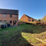 Spacious garden behind brick house on sunny day.