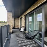 Modern balcony with chairs and striped rug.