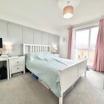 Bright bedroom with bed, desk, and large window.
