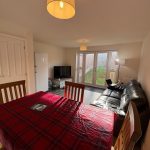 Bright living room with dining table, sofa, and TV.