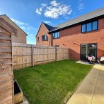 Back garden with patio and two chairs.