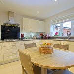 Modern kitchen with round wooden table, light cabinetry.