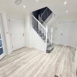 Modern hallway with wooden floor and staircase.
