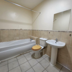 Bathroom with bathtub, toilet, sink, and mirror.