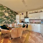 Modern kitchen with green wallpaper and dining area.
