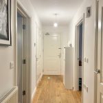 Bright hallway with wooden flooring and white doors.