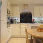 Modern kitchen with wooden table and appliances.