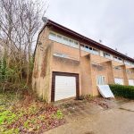 Terraced houses with garages and winter trees.
