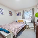 Cosy bedroom with plants, desk, and wall art.