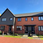 Modern red-brick terraced house in sunny UK neighbourhood.