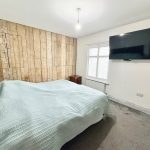 Modern bedroom with TV and wooden feature wall.